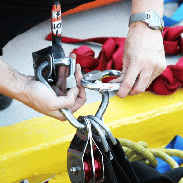 A rescuer selects equipment while practicing proper rigging.